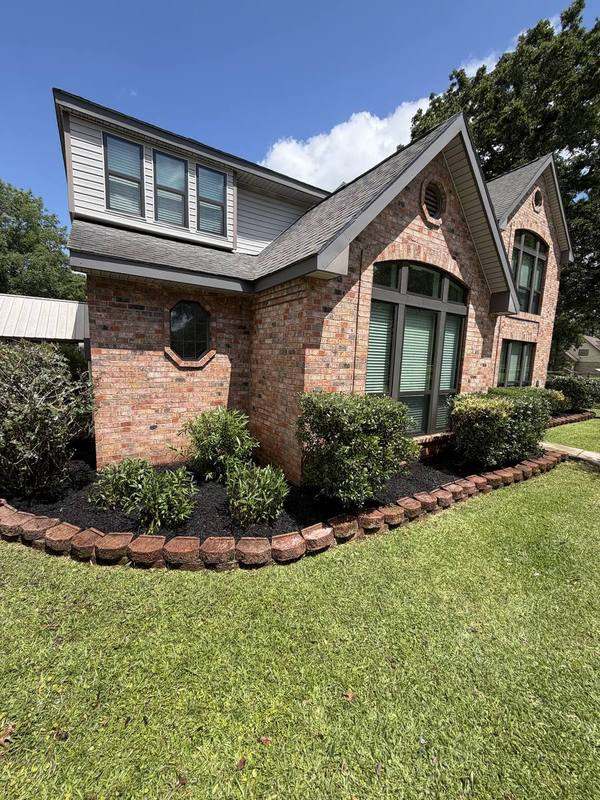 Shrub bed with crisp scalloped brick edging along a brick home